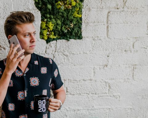 man in black top calling beside wall