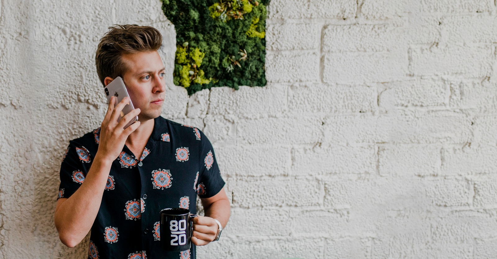 man in black top calling beside wall