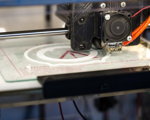 Een FDM 3D-printer met een kleurrijke filamentspoel op de achtergrond