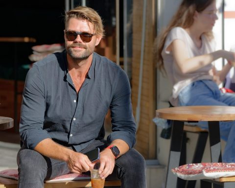 Man in licht linnen shirt en beige chino op een zomers terras