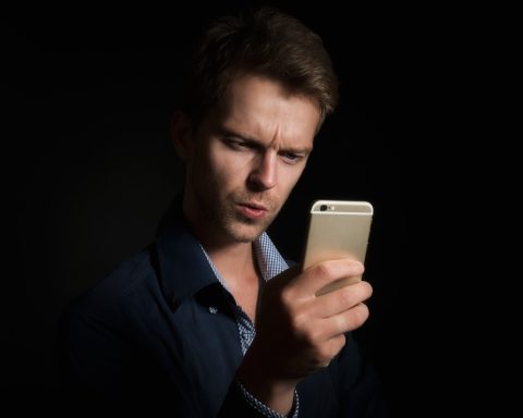 Man kijkt gefrustreerd naar een berichtje op zijn smartphone