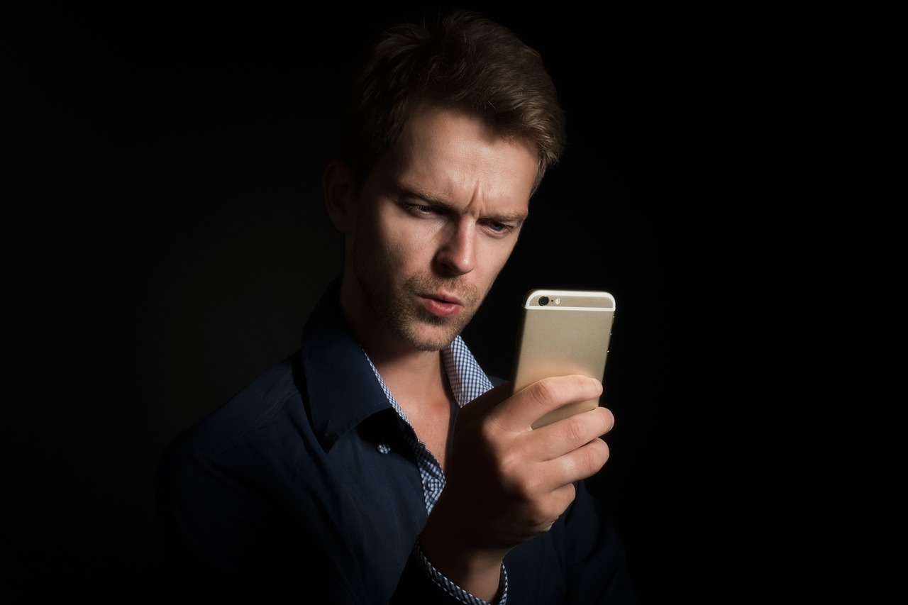 Man kijkt gefrustreerd naar een berichtje op zijn smartphone