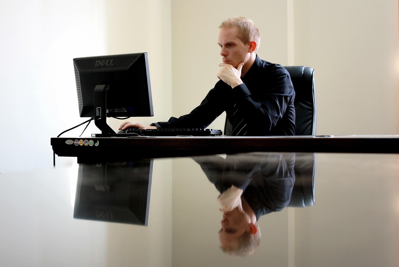 Man die peinzend achter zijn bureau zit en naar zijn laptop staart