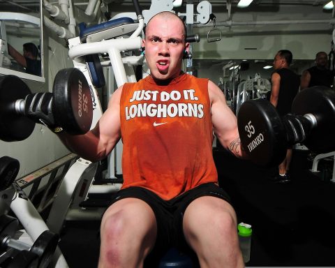 Man van middelbare leeftijd traint met dumbbells in de sportschool