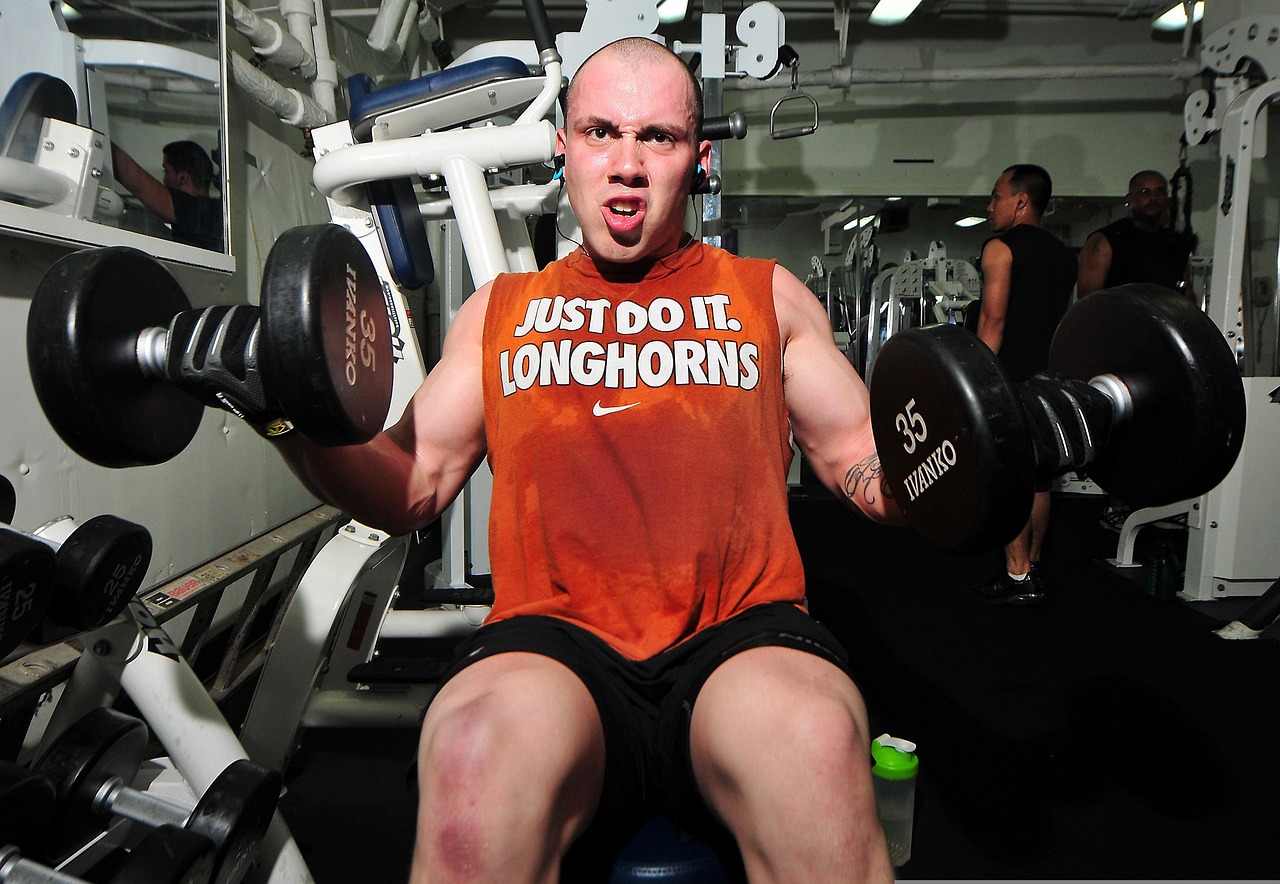 Man van middelbare leeftijd traint met dumbbells in de sportschool