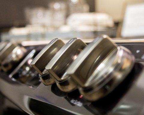 Geborsteld RVS wandpaneel achter een fornuis in een professionele keuken
