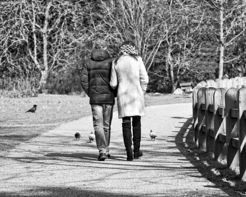Twee mannen wandelen naast elkaar door een park tijdens een gesprek
